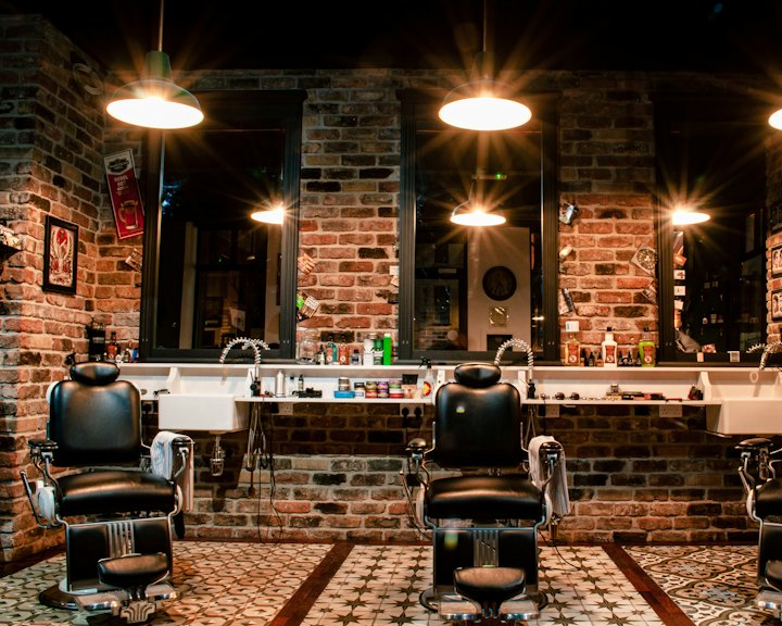 A barbershop with leather chairs, brick walls and warm lights