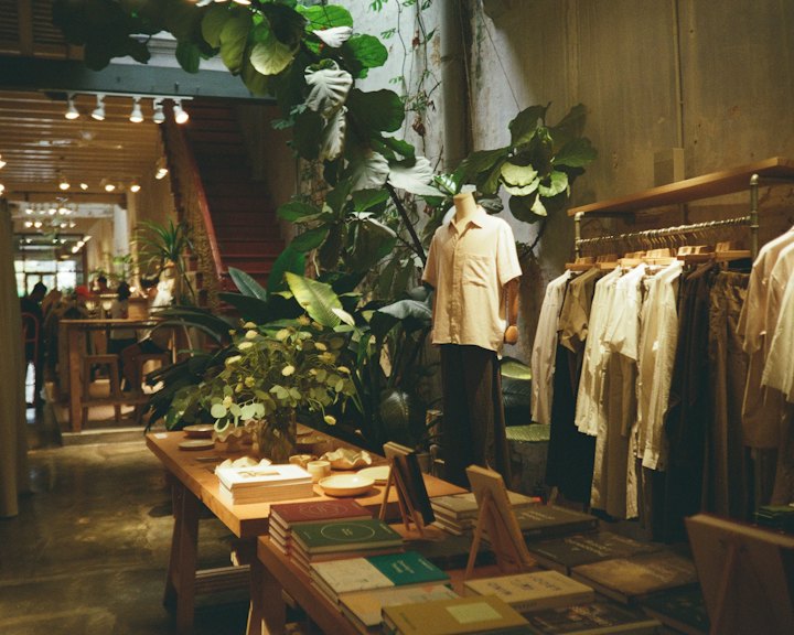 A boutique with clothing racks, plants and warm lighting