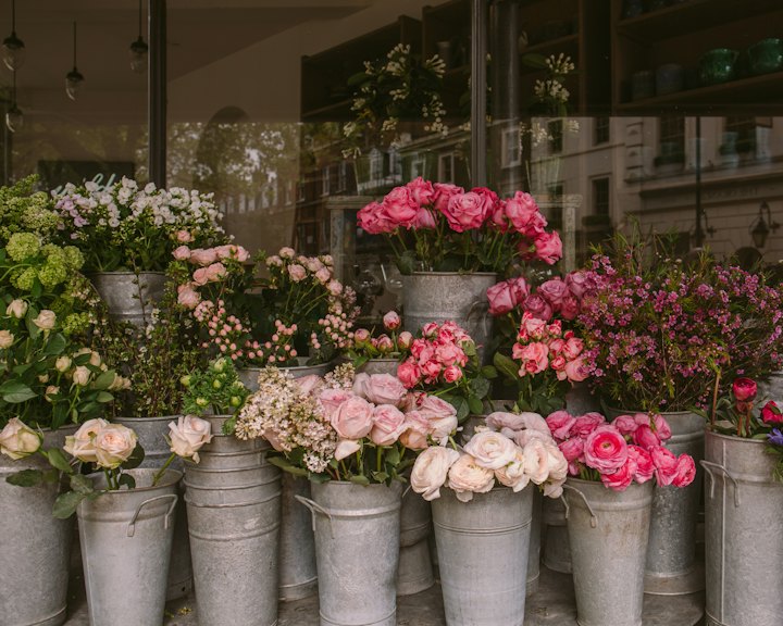 Buckets of fresh roses and peonies outside a flower shop